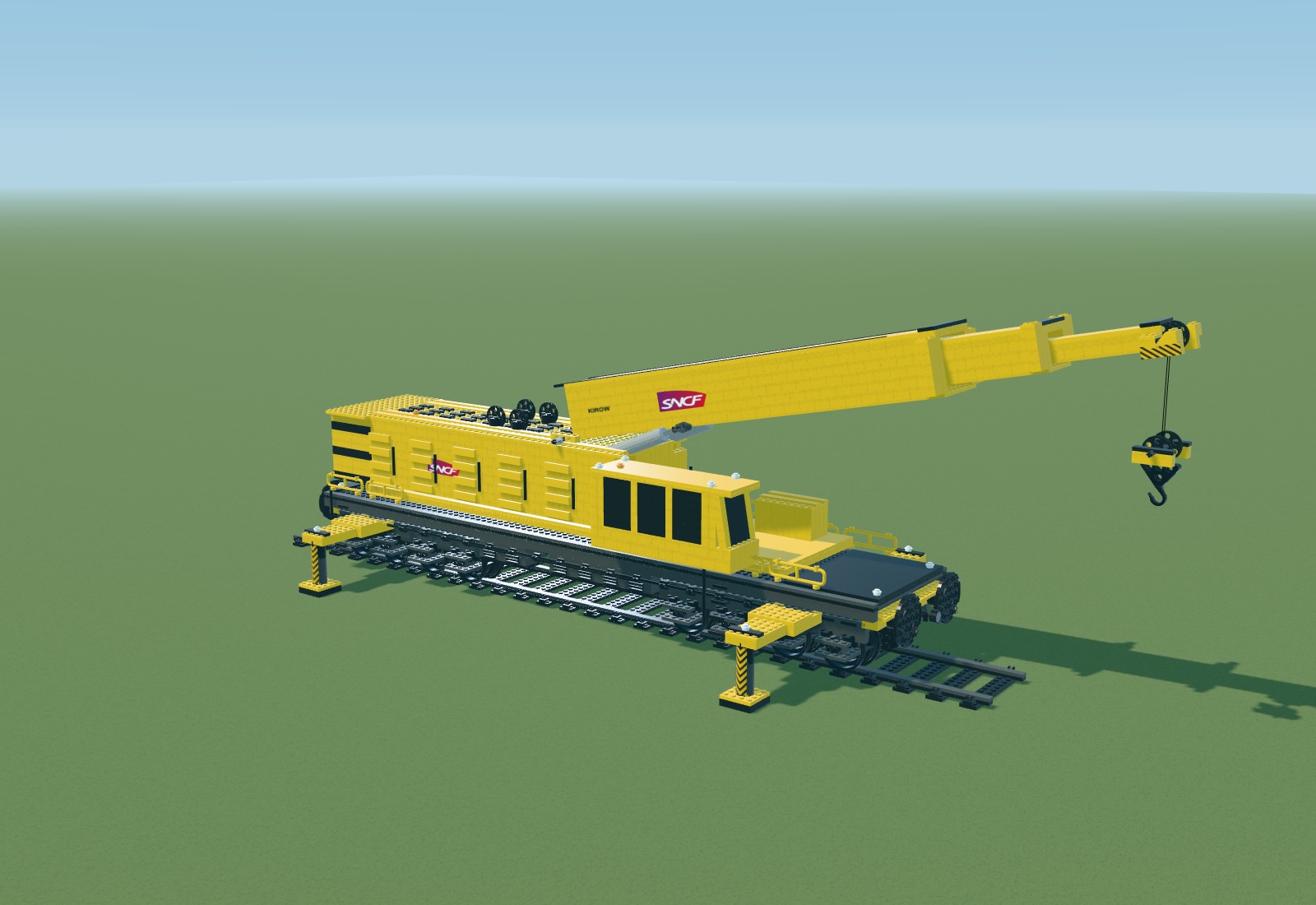 Large yellow brick model of the SNCF Kirow crane, with an asymmetric cab, eight axles, outriggers and a telescopic boom.